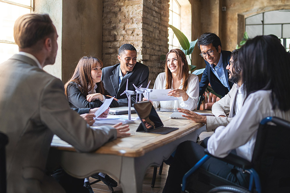 Seven colleagues discussing data on renewable energy around a table