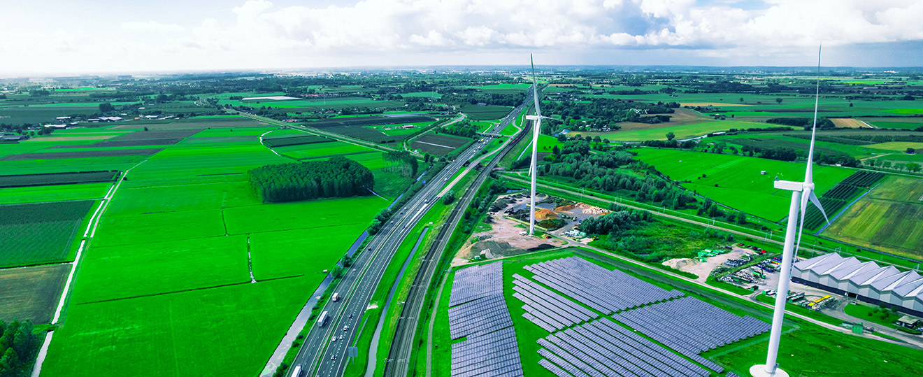 Aerial view of rural farmland with wind turbines and a solar farm, illustrating sustainable energy development
