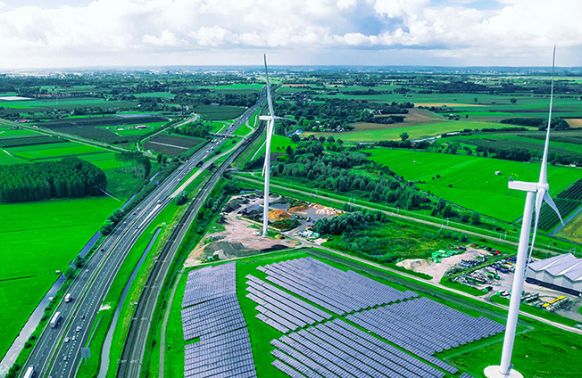 Aerial view of rural farmland with wind turbines and a solar farm, illustrating sustainable energy development
